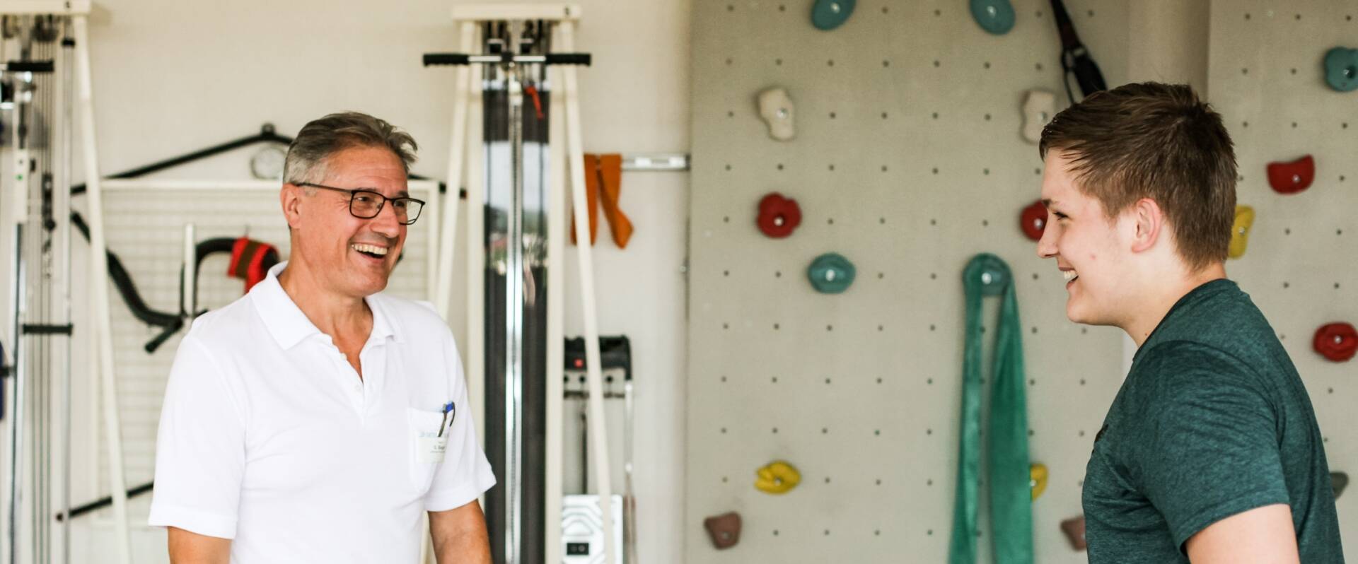 Physiotherapeut vor einer Kletterwand mit jungem Patient